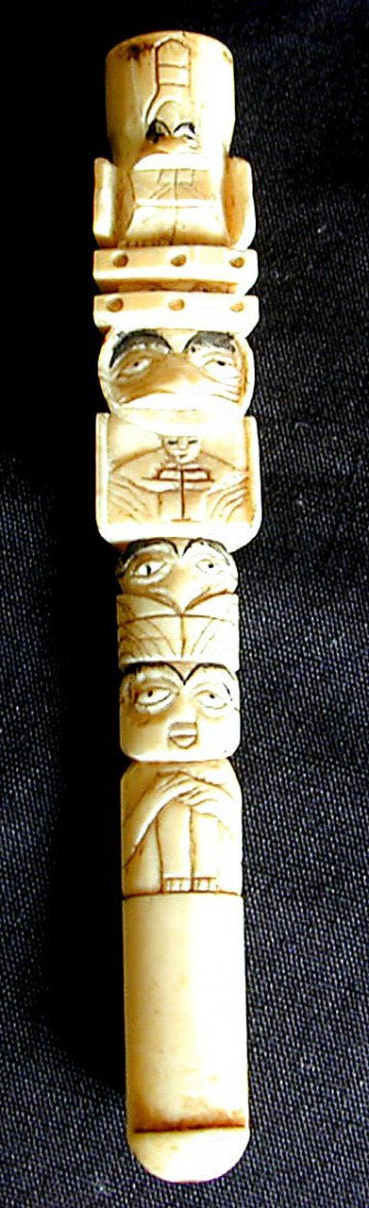 NW COAST INDIAN IVORY TOTEM CIGARETTE HOLDER: A 4" long old ivory cigarette holder in the shape of a NW Coast Indian totem pole; carved with various figures representing eagle, animals and people.