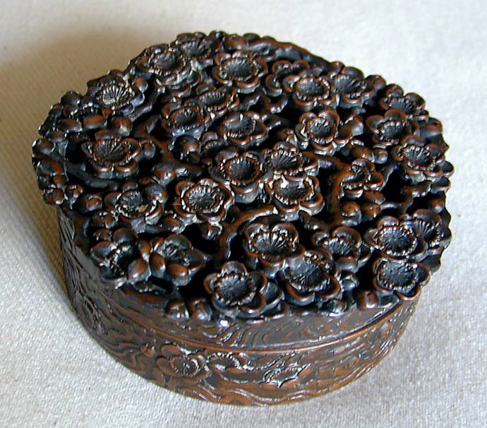 SIGNED ANTIQUE CHINESE BRONZE BOX: An antique Chinese bronze round box with the cover a reticulated design of prunus tree flowers, the box is signed in Chinese calligraphic lettering on the base, 2 5/8"D.