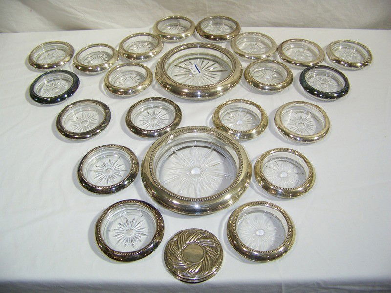23 Sterling Rimmed Glass Coasters: 23 Sterling Rimmed Glass Coasters. There is two 6 3/4" sterling rimmed and eight 3 3/4" sterling rimmed, and a 3" sterling mirror with twelve silver plate rimmed coasters.