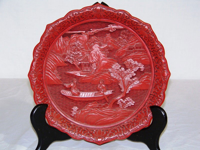 Vintage Chinese Cinnabar Landscape & Mountains Plat: Vintage Chinese Cinnabar Landscape & Mountains Plate. Great pc. with carved floral design around outer border and on verso with a scalloped edge. Has trees, women in a boat and mountain carvings.