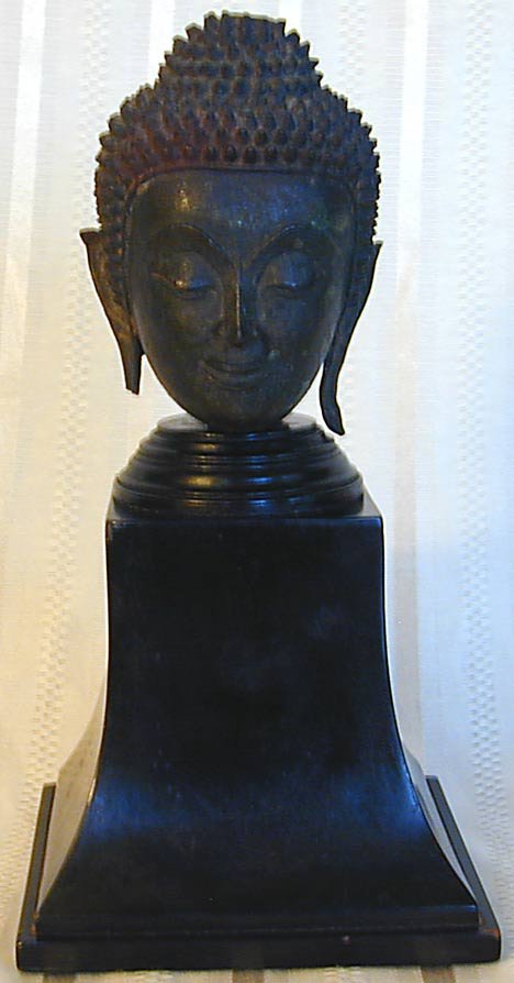 ANTIQUE THAI BRONZE BUDDHA HEAD: An antique Thai bronze head of Buddha mounted on a removable wood plinth; bronze head measures 4.5"; wood plinth measures 5.25".