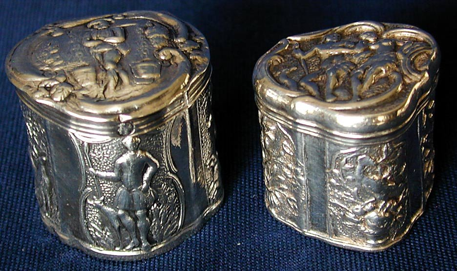 2 SMALL ANTIQUE DUTCH SILVER BOXES: A pair of antique Dutch silver patch or vanity boxes; the first a trefoil shape with repousse naturalistic scenes and marked with the axe hallmark used from 1853-1927 to denote a tax paid on older pie