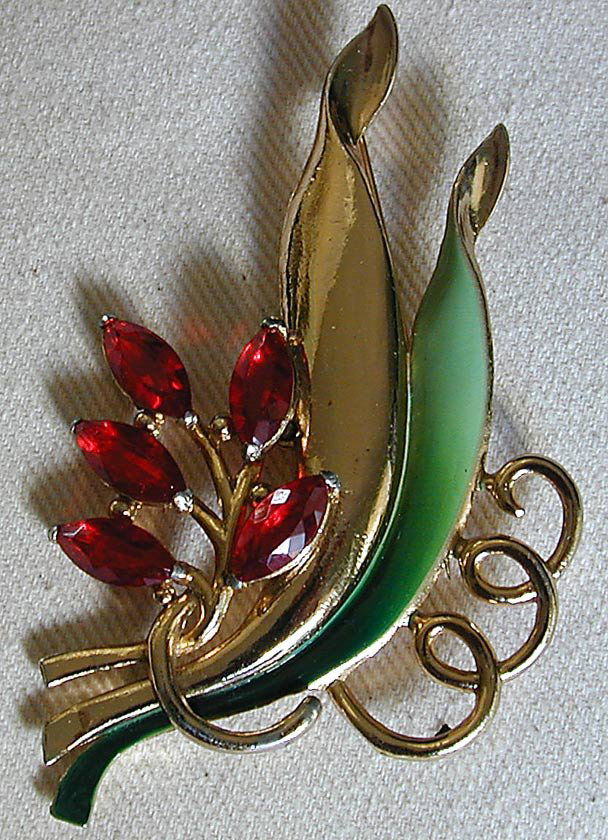CIRCA 1940 CORO PIN 4"H: A costume jewelry pin signed CORO in script depicting a green enamelled floral pin mounted with 5 red marquise shaped stones measuring 4"H, good condition.