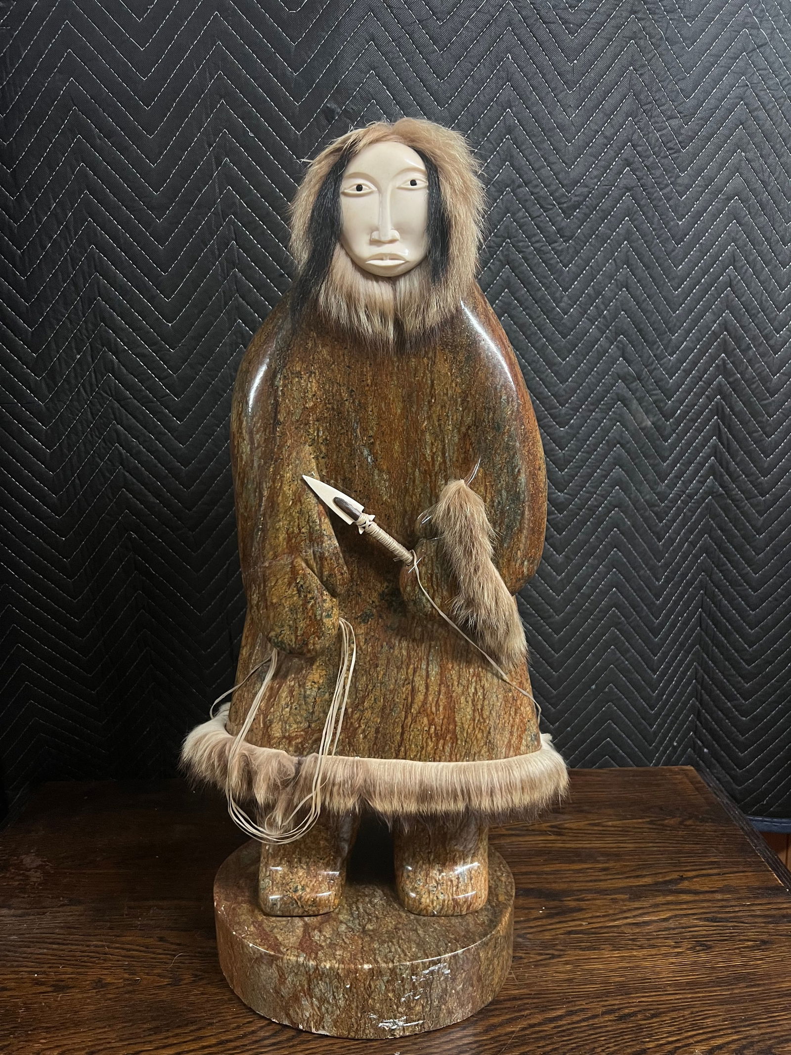 Very large Inuit stone sculpture by Michael Scott 100 lbs: Very nice stone sculpture by famed artist Michael ScottThis is an Eskimo carving of a fisherman with a fur lined stone garbHis face is carved walrus and lined with furHe holds an arrowhead spear with