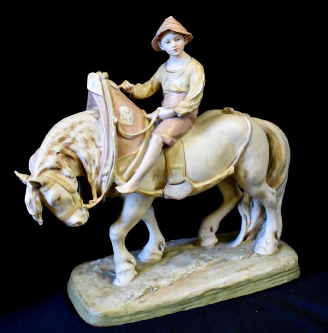 ROYAL DUX PORCELAIN SCULPTURE: Figurine of boy riding a horse features the original, raised Royal Dux applied stamp. Figure measures 14" tall x 14" long x 5" deep and appears to be in nice overall condition (fleabite chip to horse'