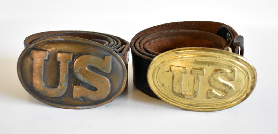 TWO US MILITARY LEATHER BELTS: One brown belt and one black belt, both with brass buckles that are embossed US.