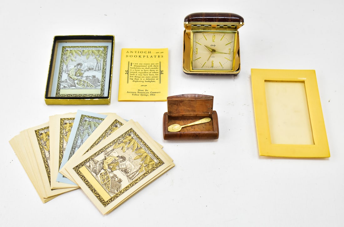 ASSORTED VINTAGE SNUFF KIT, BOOKPLATES, & MORE: An assortment of vintage pieces including a Bradley travel alarm clock, an unused pack of Antioch bookplates, a celluloid photo frame, and a burlwood snuff kit with carved bone spoon. The bookplates m