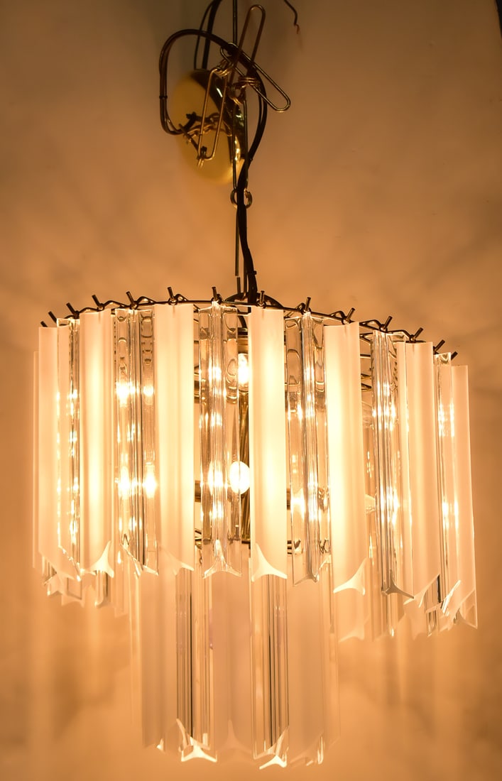 BRASS & LUCITE PRISM CHANDELIER: Six socket brass chandelier with clear and frosted Lucite hanging prisms. Measures 17” x 17” without the chain.