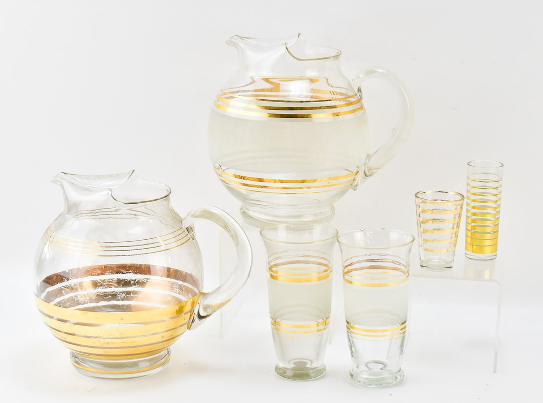 MIDCENTURY GILDED & FROSTED GLASS PITCHERS & CUPS: A pair of midcentury gilded glass pitchers, a pair of similar style tumbler cups in frosted glass, and a pair of shit glasses. The pitchers measure 8 inches in height.