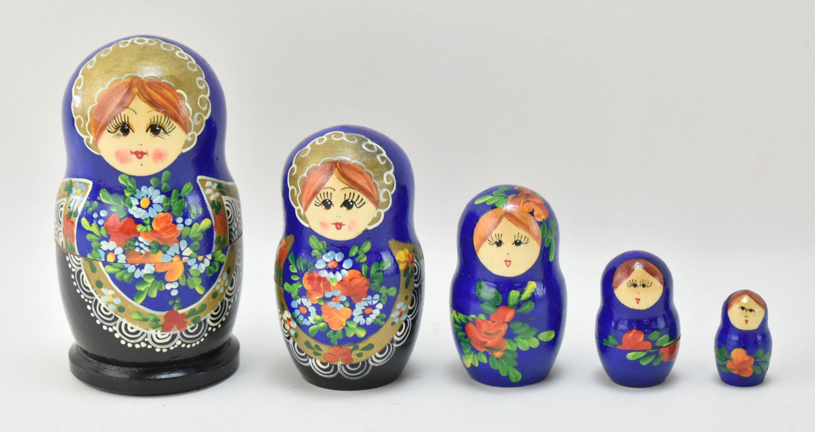HAND-PAINTED RUSSIAN NESTING DOLLS: Five hand-painted wooden Russian nesting dolls, circa mid-20th century. Dolls measure 1" to 5.5" tall.