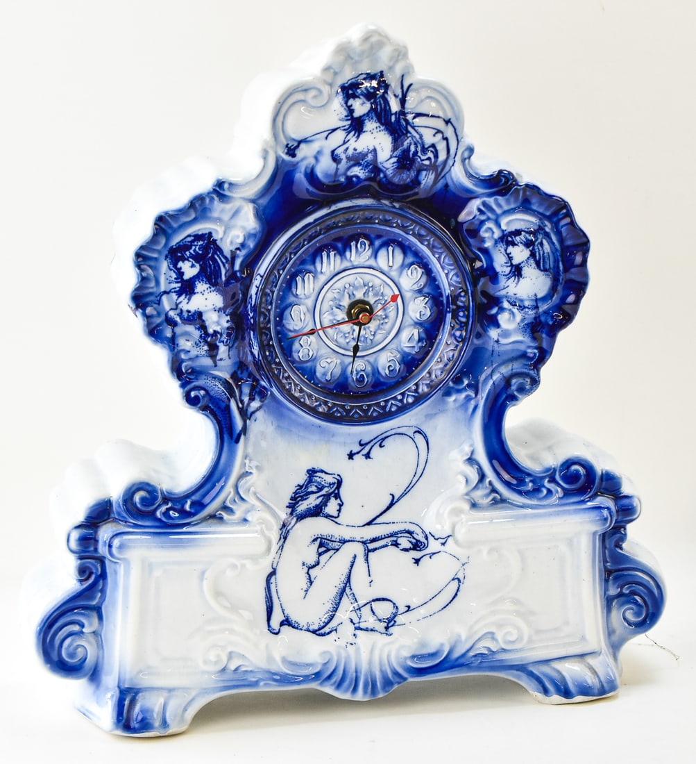 CONTEMPORARY PORCELAIN FLOW BLUE NUDE MANTLE CLOCK: Contemporary porcelain flow blue mantle clock with nude figures. The clock measures 16" H x 15.5" W x 4" D.