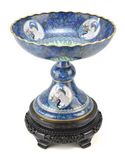 CHINESE CLOISONNE TAZZA, EARLY 20TH CENTURY: A Chinese export cloisonne tazza on ebonized wooden stand with filigree scrollwork, crane, and Mandarin duck motifs, circa early 20th century. The tazza measures 19" H x 16.5" D.