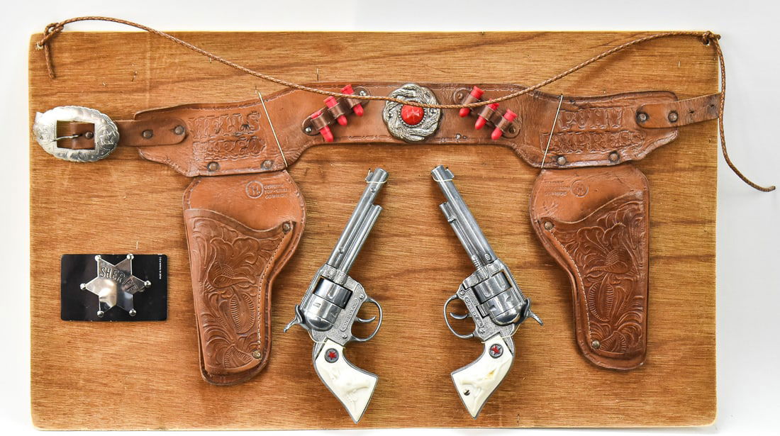 PAIR OF HUBLEY COWBOY JR. REVOLVER CAP GUNS & SHERIFF BADGE: A pair of Hubley Cowboy Jr. revolver cap guns made in the USA in the late 1950s, with a double holster and a Sheriff star badge.