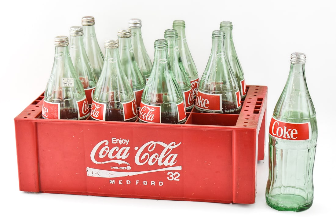 12 VINTAGE COCA-COLA ONE QUART BOTTLES: MADISONVILLE AND ATLANTA BOTTLING: This lot includes 12 Coca-Cola one quart bottles (Madisonville, Kentucky; Atlanta, Georgia), circa late 20th century. The lot measures 13" heigh, 19" wide, and 12.5" deep.
