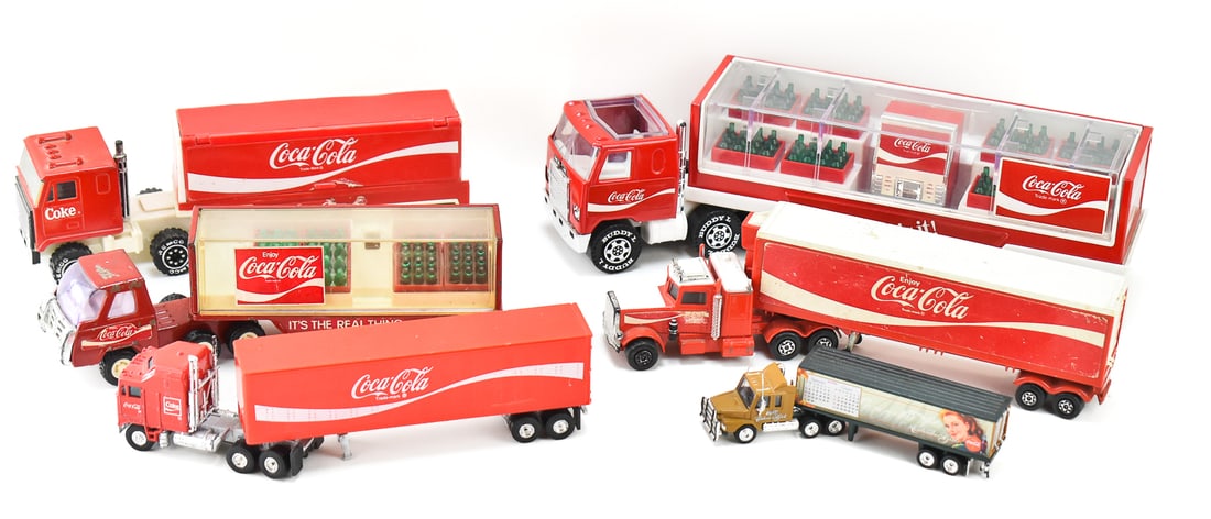 COLLECTION OF COCA-COLA TOY DELIVERY TRUCKS: Six Coca-Cola toy delivery trucks include a 1980 Buddy "L", a 1970s matchbox SuperKings, a 1987 Remco Toys, a 1986 Buddy "L" made in Japan, a Matchbox "Calender Girls", and a Yatming, China semi truck