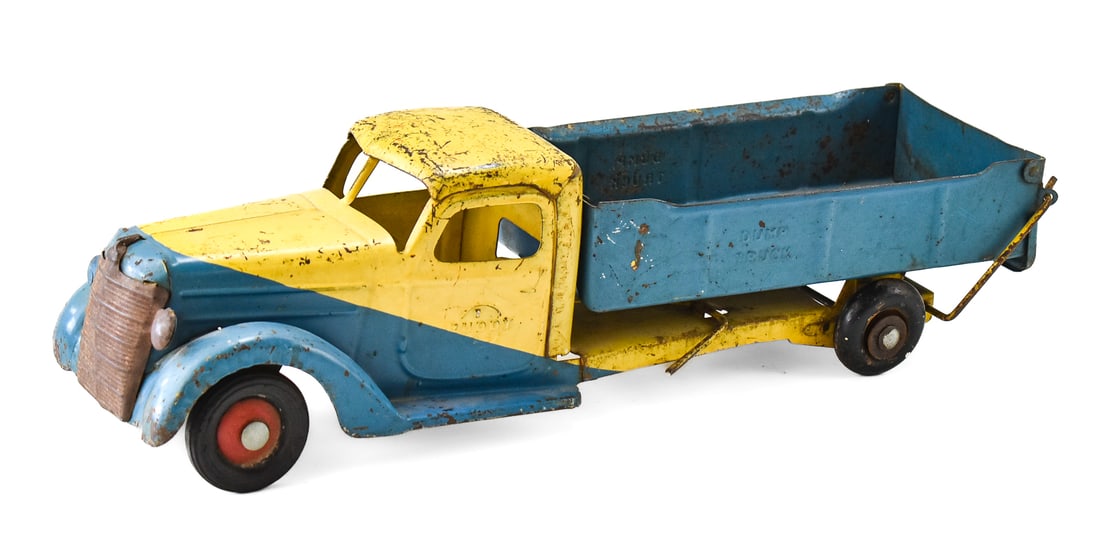 VINTAGE BUDDY L PRESSED STEEL DUMP TRUCK TOY: A Buddy L pressed steel dump truck toy, circa 1930-1940s. The toy measures 6" heigh, 6" wide, and 21" deep.