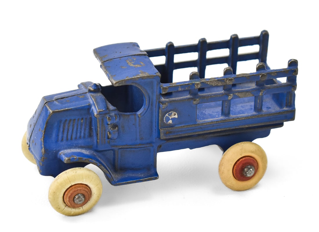 A.C. WILLIAMS BLUE STAKE-BODY CAST IRON TRUCK TOY: An A.C. Williams blue stake-body cast iron truck toy "1560", circa 1930s. The toy measures 2.5" heigh, 4.5" wide, and 2" deep.