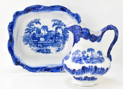 STAFFORDSHIRE "ROMANTIC" FLOW BLUE PITCHER & BASIN: Two pieces of 1970s or later Blakney Pottery of Staffordshire "Romantic" pattern flow blue ironstone pitcher and basin. The pitcher measures 11" H x 10" W x 8" D, and the basin is 5" H x 15" W x 13" D