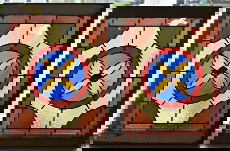 TWO STAINED GLASS WINDOWS: A pair of antique stained glass windows with geometric flower motifs in original wood frames. The largest measures 26.5" H x 20" W x 2" D
