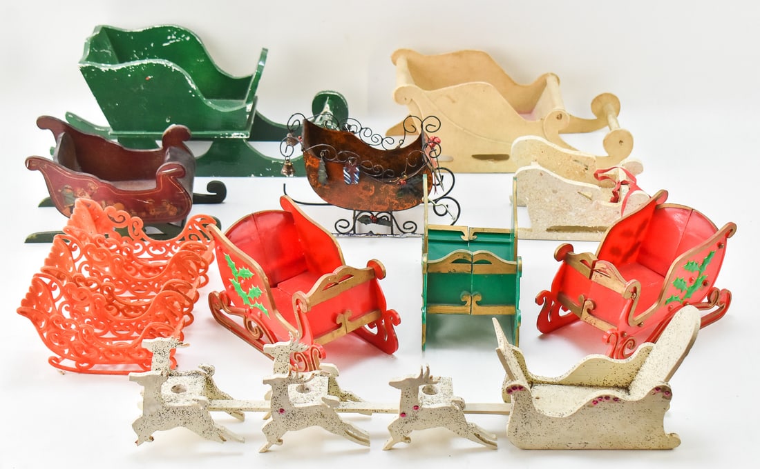 COLLECTION OF WOODEN, PLASTIC, & METAL SLEIGHS: Collection of wooden, metal, plastic, and flocked felt Santa sleighs. The largest green sleigh measures 6" H x 14" W x 4" D.