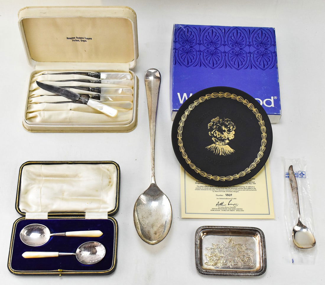 ASSORTED SILVERPLATE UTENSILS & WEDGWOOD MT. ST. HELENS 1980 ERUPTION COMMEMORATIVE PLATE: This lot includes a collection of silverplate utensils, some of which include faux pearl handles, and a Wedgwood bisque porcelain plate commemorating the 1980 eruption of Mt. St. Helens. The plate mea