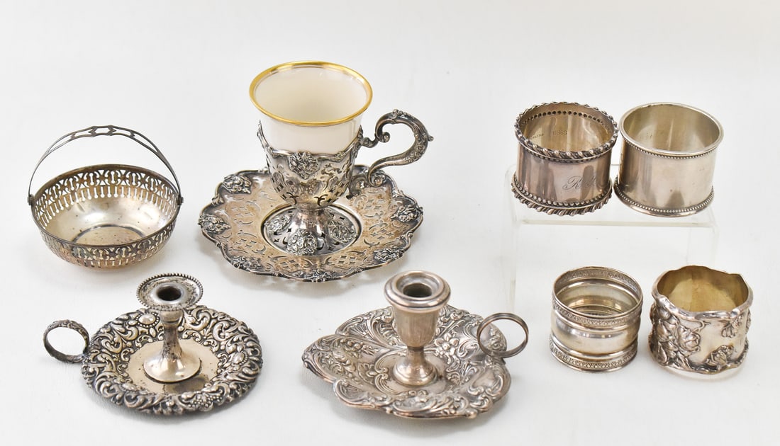 ASSORTED STERLING SILVER TABLEWARE & PORCELAIN EGG CUP: An assortment of sterling silver tableware such as candlesticks, condiment basket, napkin rings, and an egg cup. The egg cup includes a Lenox porcelain insert. For reference, the egg cup measures 3" H