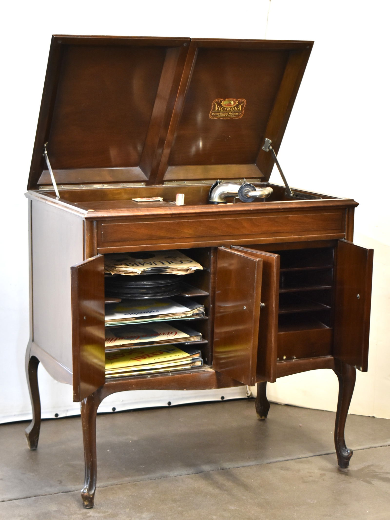 ANTIQUE VICTOR TALKING MACHINE CO. 'VICTROLA' PHONOGRAPH CABINET: An antique Victor Talking Machine Co. "Victrola" wind-up phonograph cabinet complete with the phonograph, spare needles, storage compartments, tabletop, and a collection of 78 rpm 10" records. The cab