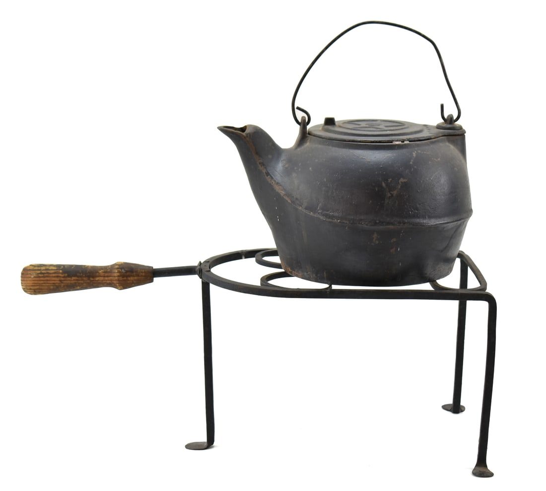 19TH C. CAST IRON CHATTANOOGA STAR 8 KETTLE & TRIVET: A late 1800s Chattanooga Stove Co. Star #8 cast iron kettle, and a wrought iron standing trivet with wooden handle. The kettle measures 8" H x 12" W x 9" D and the trivet is 9.5" H x 21.5" W x 1" D.