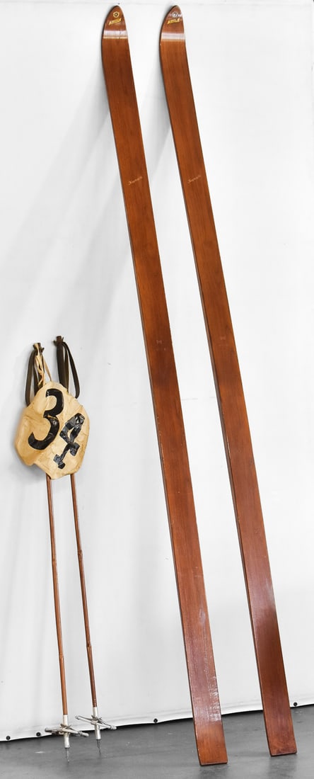 VINTAGE KONGSBERG 'SUPER' 245 PAIR OF SKIS WITH POLES: A Kongsberg "Super" 245 pair of skis No. 6563 with poles and racing number "34", circa mid 20th century. The item measures 96" H, 3.5" W, 4" D.