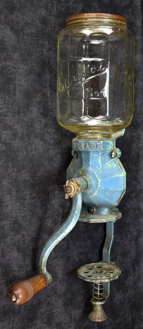 ANTIQUE ARCADE NO. 40 WALL-MOUNT COFFEE GRINDER: An antique Arcade No. 40 wall-mount coffee grinder with the original coffee feeding jar. The grinder measures 12.25" H.