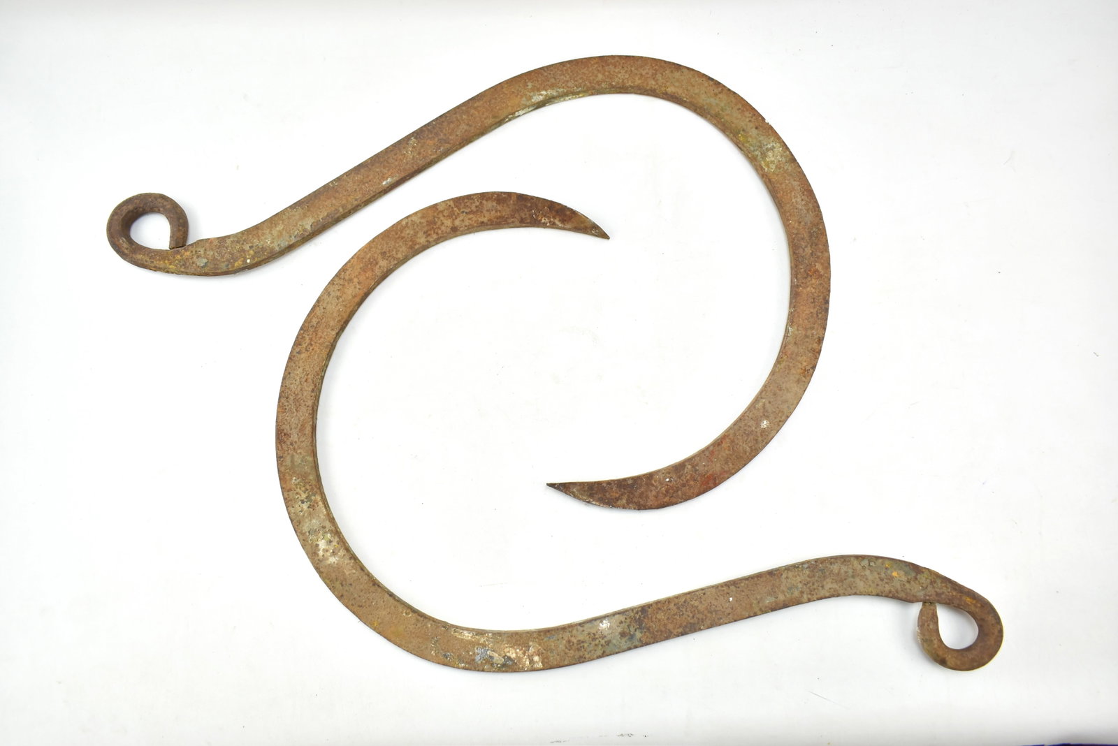 TWO 19TH CENTURY CAST IRON HOOKS: This lot includes two cast iron hooks possibly for logging or hay, circa 19th century. The item measures 27" H, 20.5" W, 1" D.