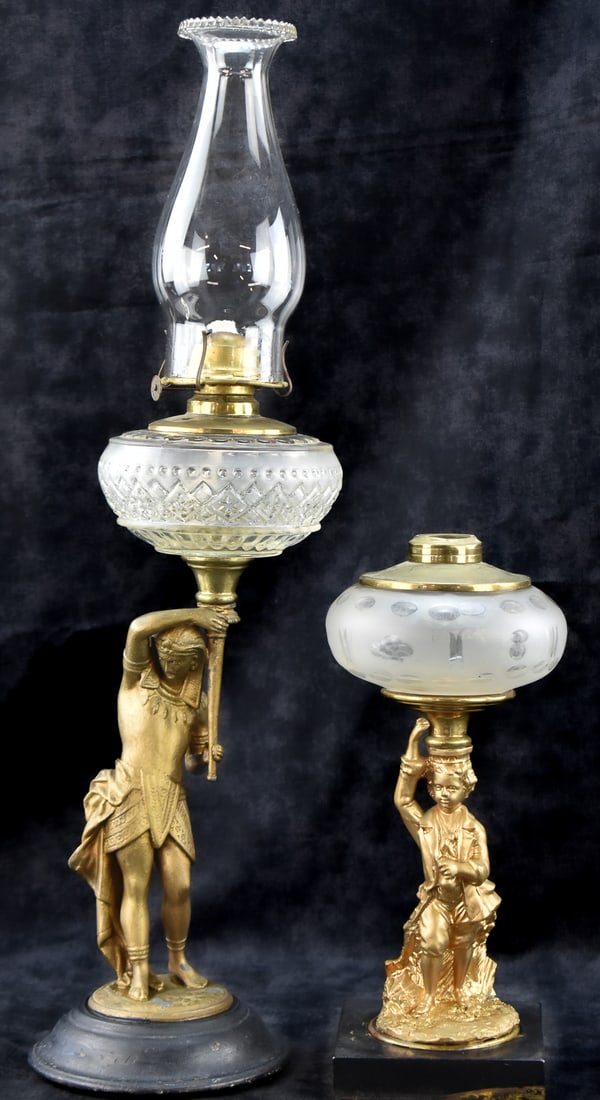 VICTORIAN FIGURAL STEMMED OIL LAMPS: COLONIAL BOY & PHARAOH: This lot includes a colonial dressed boy figural oil lamp and an Egyptian Revival figural pharaoh oil lamp with a Plume & Atwood Manufacturing Company "Eagle" burner, circa late 19th century. The 