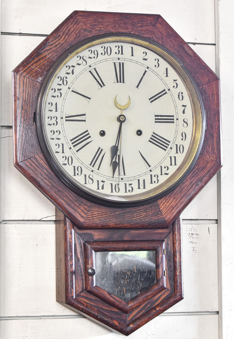 ANTIQUE WATERBURY CLOCK CO. REGULATOR OAK WALL CLOCK: A late 1800s to early 1900s antique Waterbury Clock Co. regulator oak wall clock with pendulum and key, measuring 24"H x 16"W x 4.75"D.