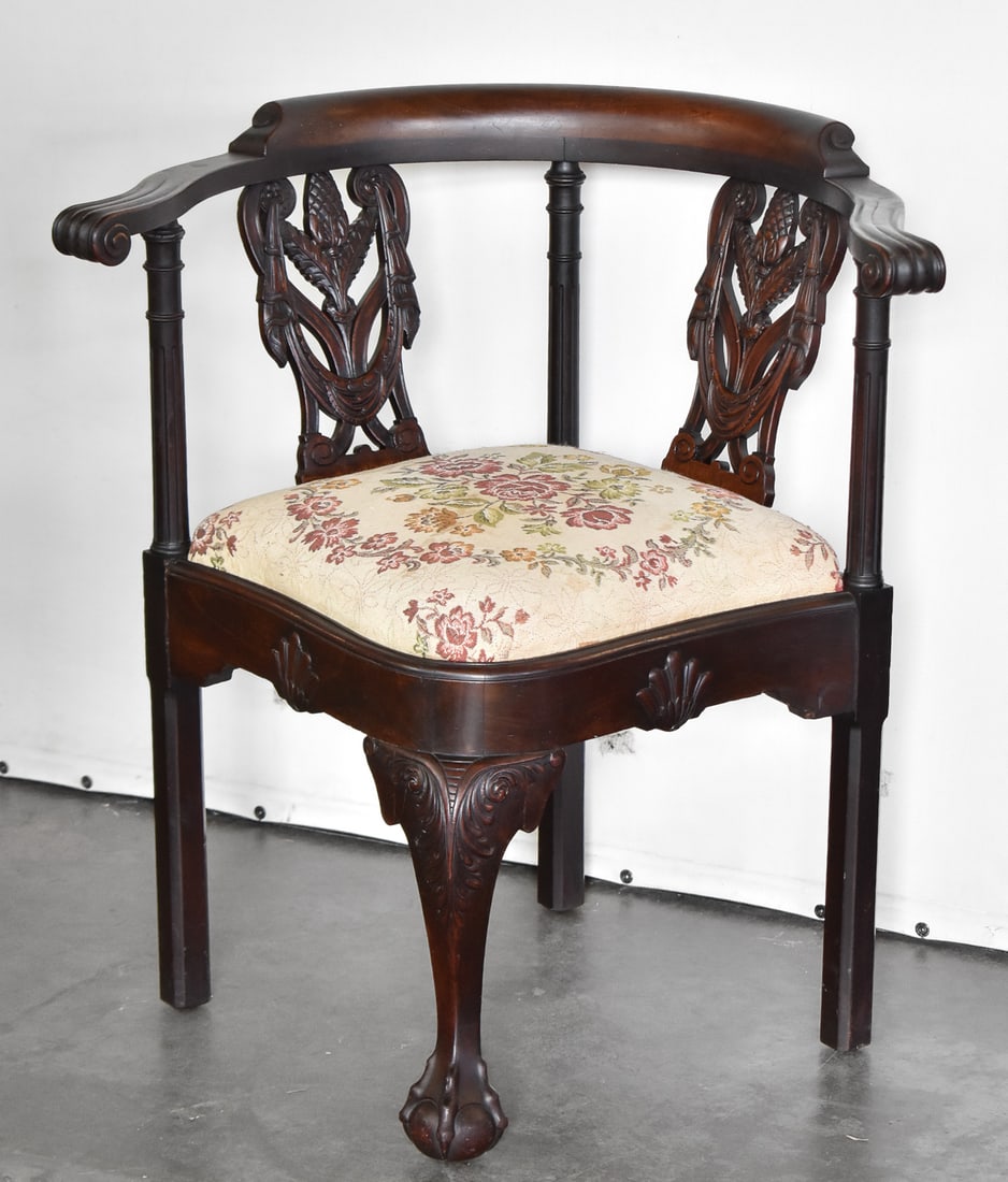 19TH C. CARVED MAHOGANY CORNER CHAIR: A late 1800s carved back mahogany corner chair with middle claw and ball foot and floral needlepoint seat, measuring 31" H x 29" W x 25" D.