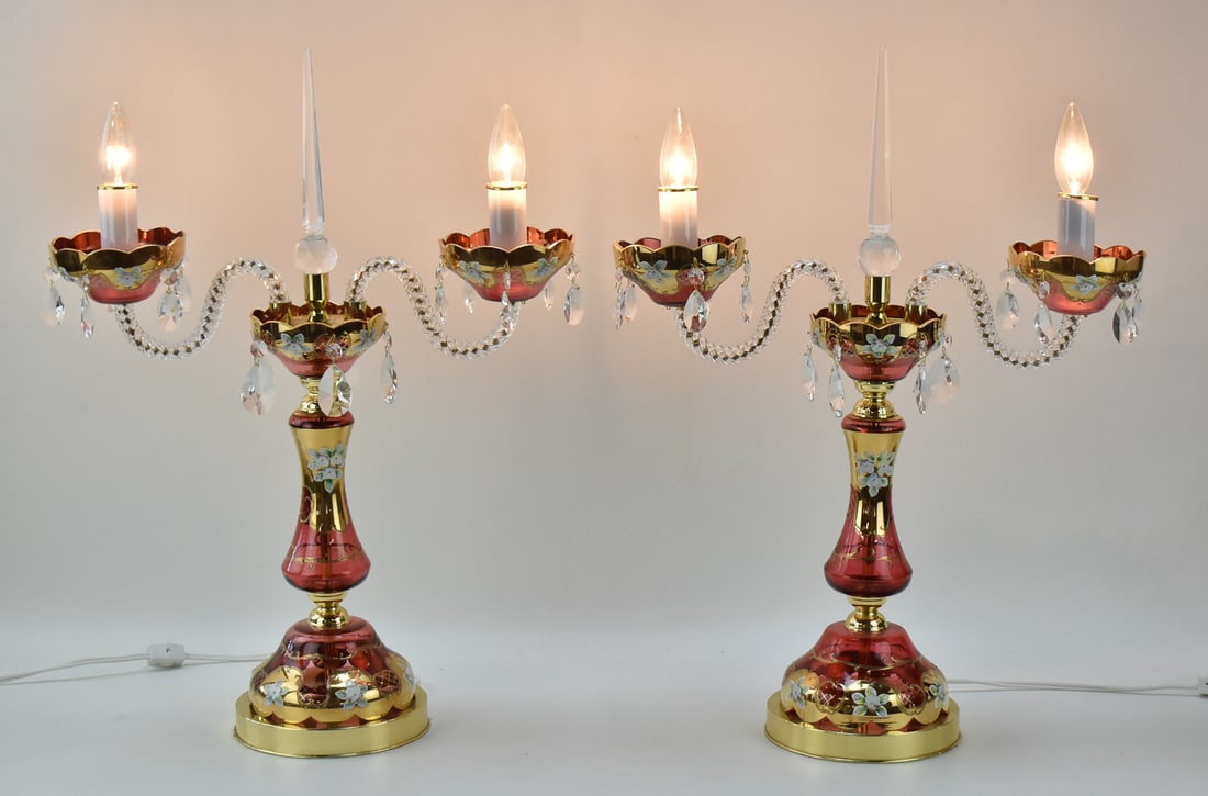 PAIR OF CZECH RUBY GLASS & GILT-ENAMEL CANDELABRA LAMPS: Two vintage Czech two-arm ruby glass candelabra lamps with gilt-enamel decoration, and crystal prisms. Each lamp measures 24" H x 18" W x 7" D.