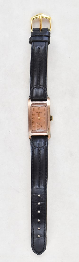 WITTNAUER TANK CURVE 10K GOLD-FILLED WATCH: A Wittnauer 10k gold-filled tank curve hand-wind wrist watch with sub-second movement, circa 1940s. The watch has a genuine black leather band. The watch case is 1.5" H x 0.75" W x 0.25" D.