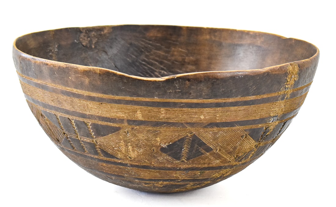 WEST AFRICAN TUAREG INCISED GEOMETRIC PATTERN TOMMUDE BOWL: A West African Tuareg incised geometric patterned wooden tommude (milk bowl), circa early 20th century. The item measures 6.5" H x 13.5" W x 13.5" D.