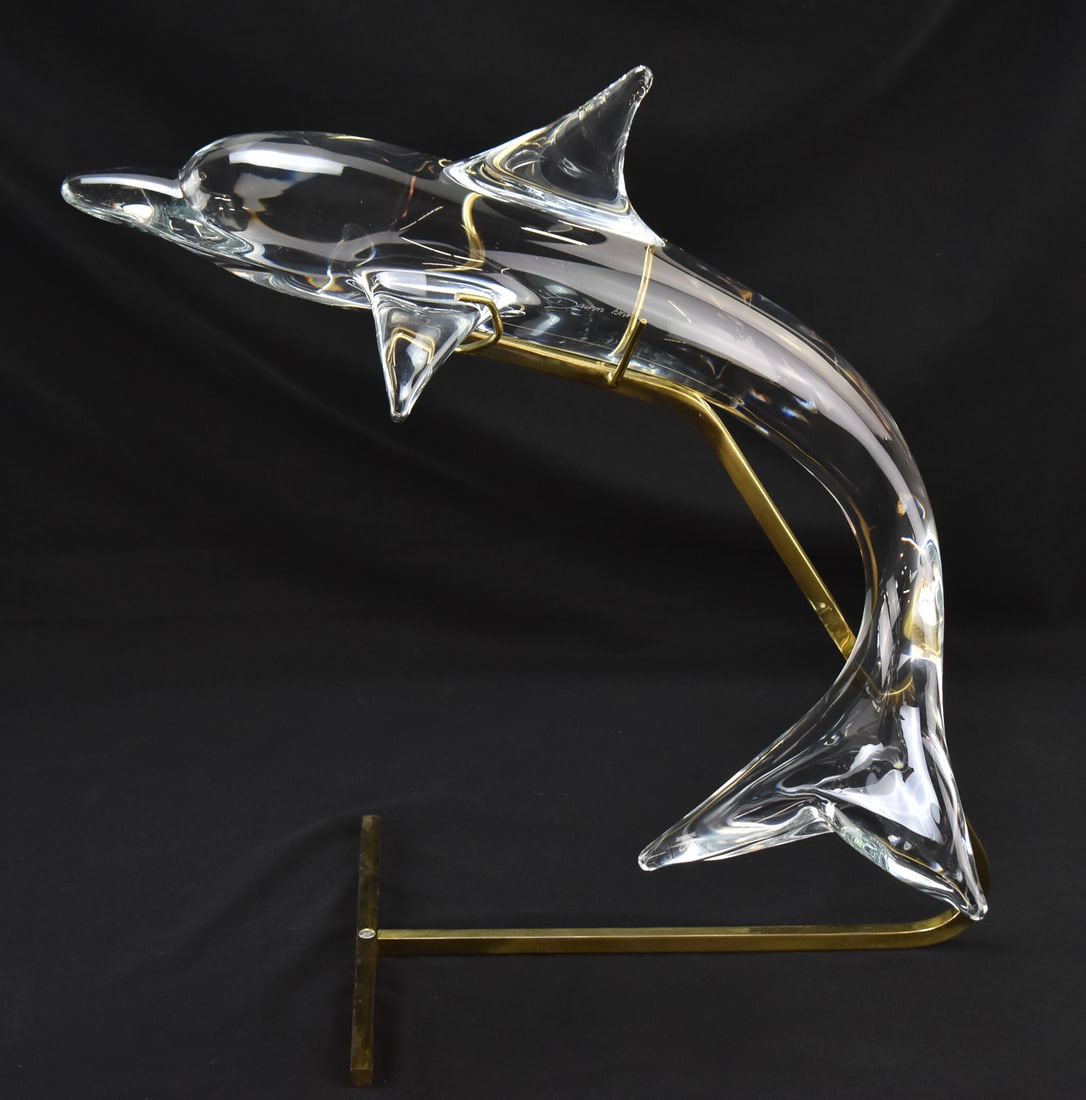 POSTMODERN SCULPTED CRYSTAL DOLPHIN BY DAUM FRANCE: A Postmodern sculpted crystal dolphin by Daum France on a gold colored stand, measuring 19"H x 14"W x 9"D.