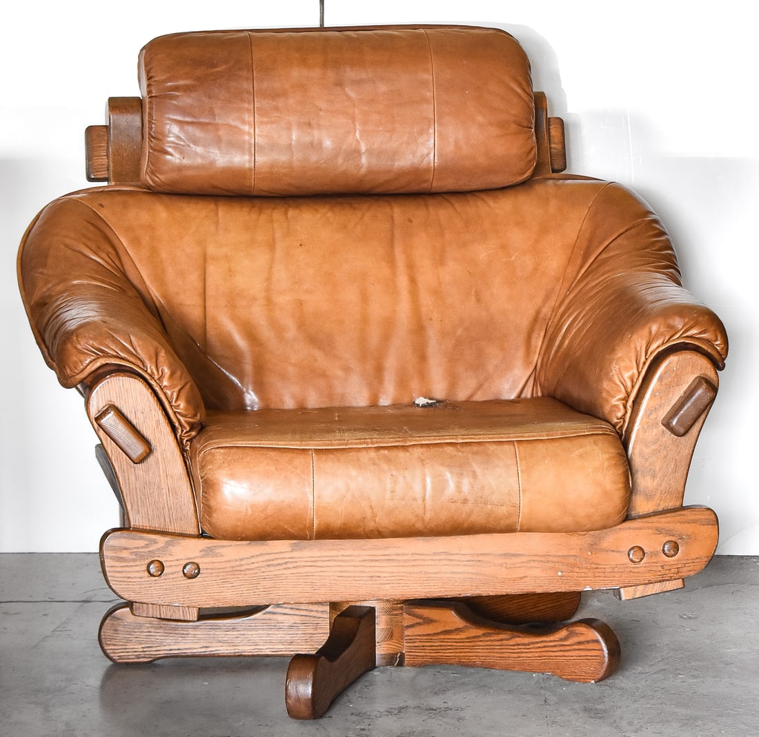 MID-CENTURY DUTCH OAK & LEATHER SWIVEL LOUNGE CHAIR: A 1970s oak and leather generously sized lounge chair that rocks and swivels, potentially of Dutch make, measuring 31"H x 39"W x 39"D.