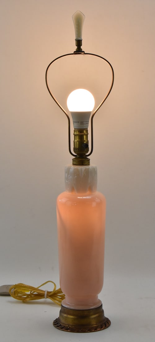 MID-CENTURY WHITE AND PINK CERAMIC LAMP BY ALADDIN: A Mid-century pink and white ceramic lamp with a brass base made by Aladdin, circa 1930s-1950s. Includes an original matching lamp shade finial. The lamp measures 27.5" H x 4.5" W x 4.5" D.