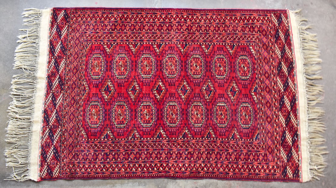 TEKKE TURKMEN WOOL RUG: A Tekke Turkmen wool rug originating from the Turkmen tribes of Turkmenistan, Afghanistan, and Iran, circa early 20th century. This rug has an exceptionally long fringe, repeating geometric