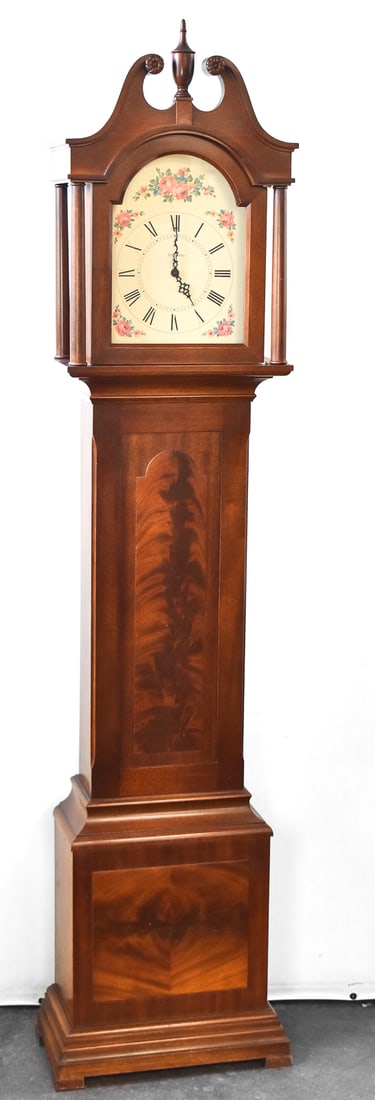 SETH THOMAS GRANDMOTHER CLOCK: A Seth Thomas Grandmother clock with a mahogany case and a floral motif on the face. The clock measures 70"H x 16"W x 7"D.