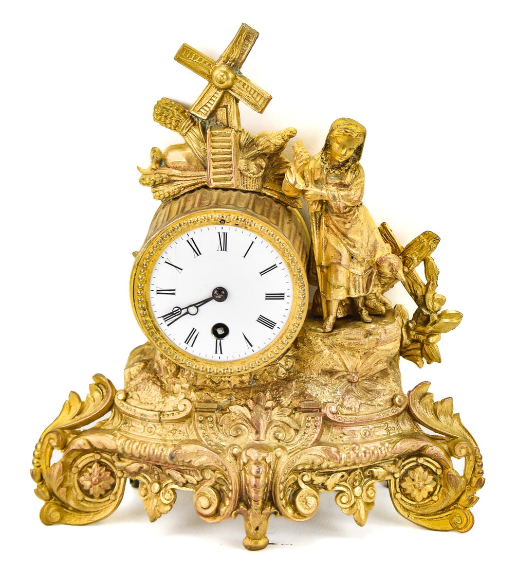 FRENCH GILT METAL TABLE CLOCK; CIRCA TURN OF 19TH CENTURY: A French gilt metal table clock featuring a woman alongside a windmill, circa turn of the 19th century; with a pendulum, key, and marked "HB". The item measures 11" H, 10" W, 3.5" D.