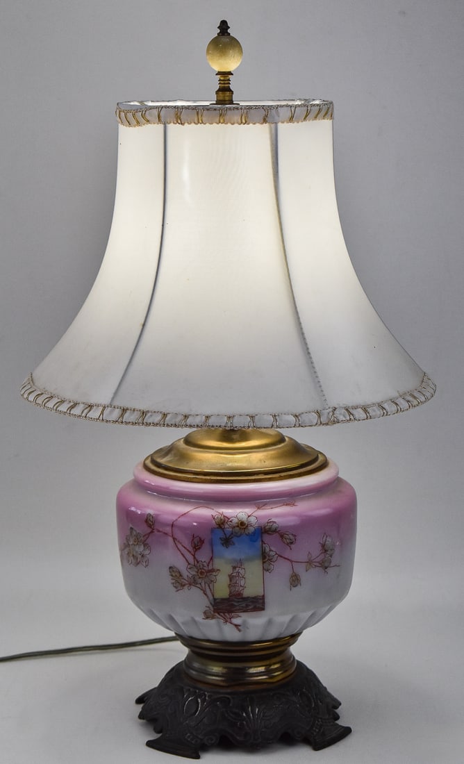 ANTIQUE HAND-PAINTED 'CLIPPER SHIP & FLORAL' TABLE LAMP: A antique table lamp hand painted with a clipper ship and floral design. The lamp has brass accents and a cast iron base. The measurements including the shade are 20"H x 12"W x 12"D.