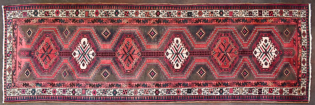 PERSIAN SERAB WOOL RUNNER RUG: A Persian Serab wool runner rug, circa early 20th century. The rug features a six geometric traditional patterned medallions, beige, pink, and blue colors, and a trimmed fringe. The rug measures