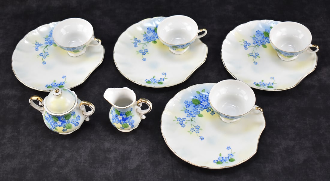 VINTAGE LEFTON 'FORGET ME NOT' HAND-PAINTED SNACK SET: A 1950s Lefton "Forget Me Not" hand-painted snack set which includes: four snack plates, four tea or coffee cups, one sugar bowl with lid, and one creamer. The plates measure 0.5" H x 8" W x 8" D.