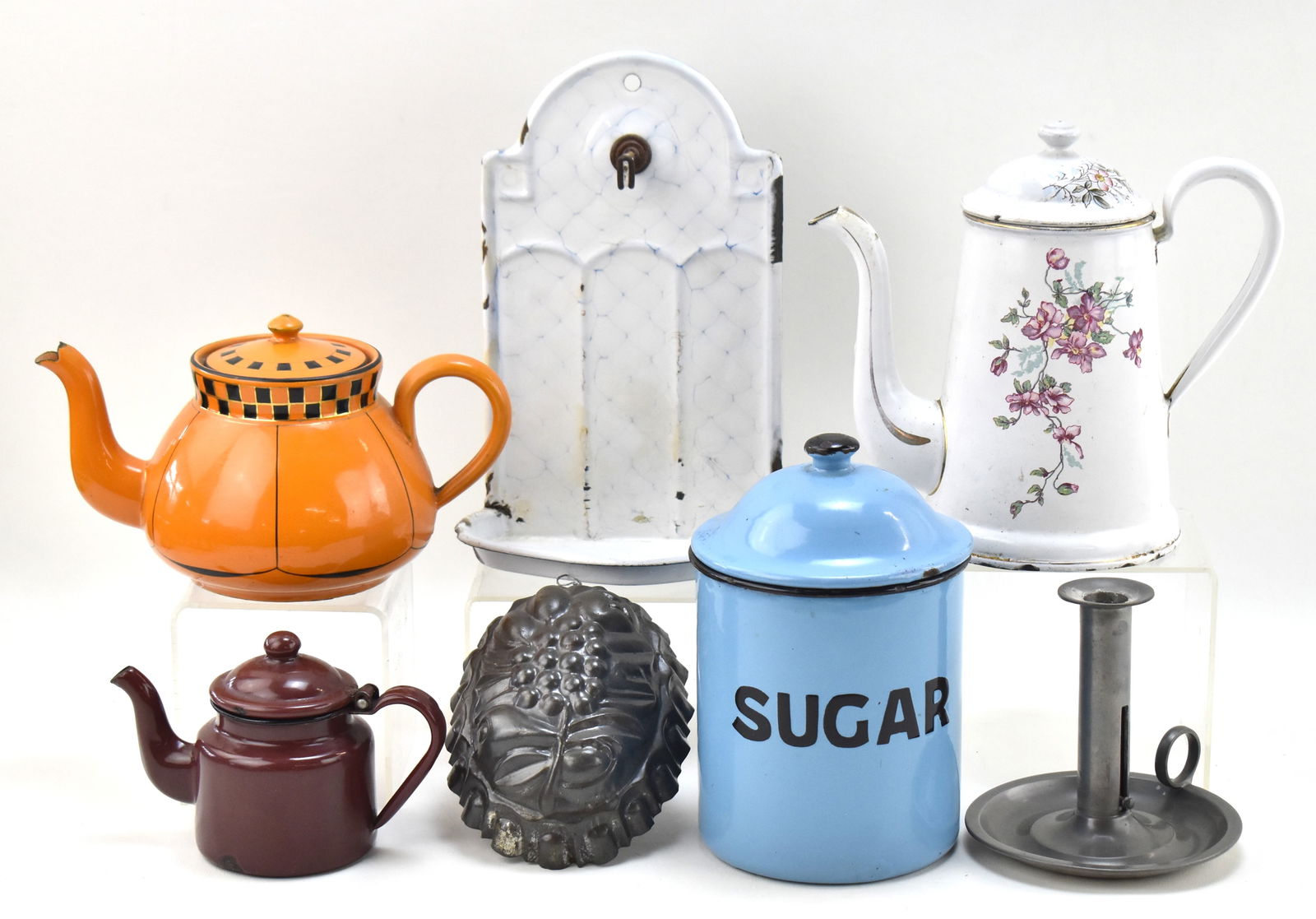 EARLY 20TH CENTURY KITCHENWARE ASSORTMENT: GERMAN SOAP DISH, REED & BARTON CANDLESTICK, & MORE: This lot includes the following, circa early 20th century: B&W floral pattern coffee pot, German-made orange and black checkered pitcher, a gelatin mold, enamelware "Sugar" canister, German