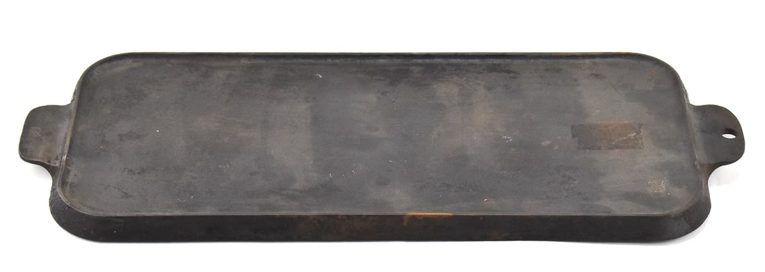GRISWOLD CAST IRON GRIDDLE: A Griswold cast iron griddle No. 745A. The item measures 0.5" H, 22" W, 9" D.
