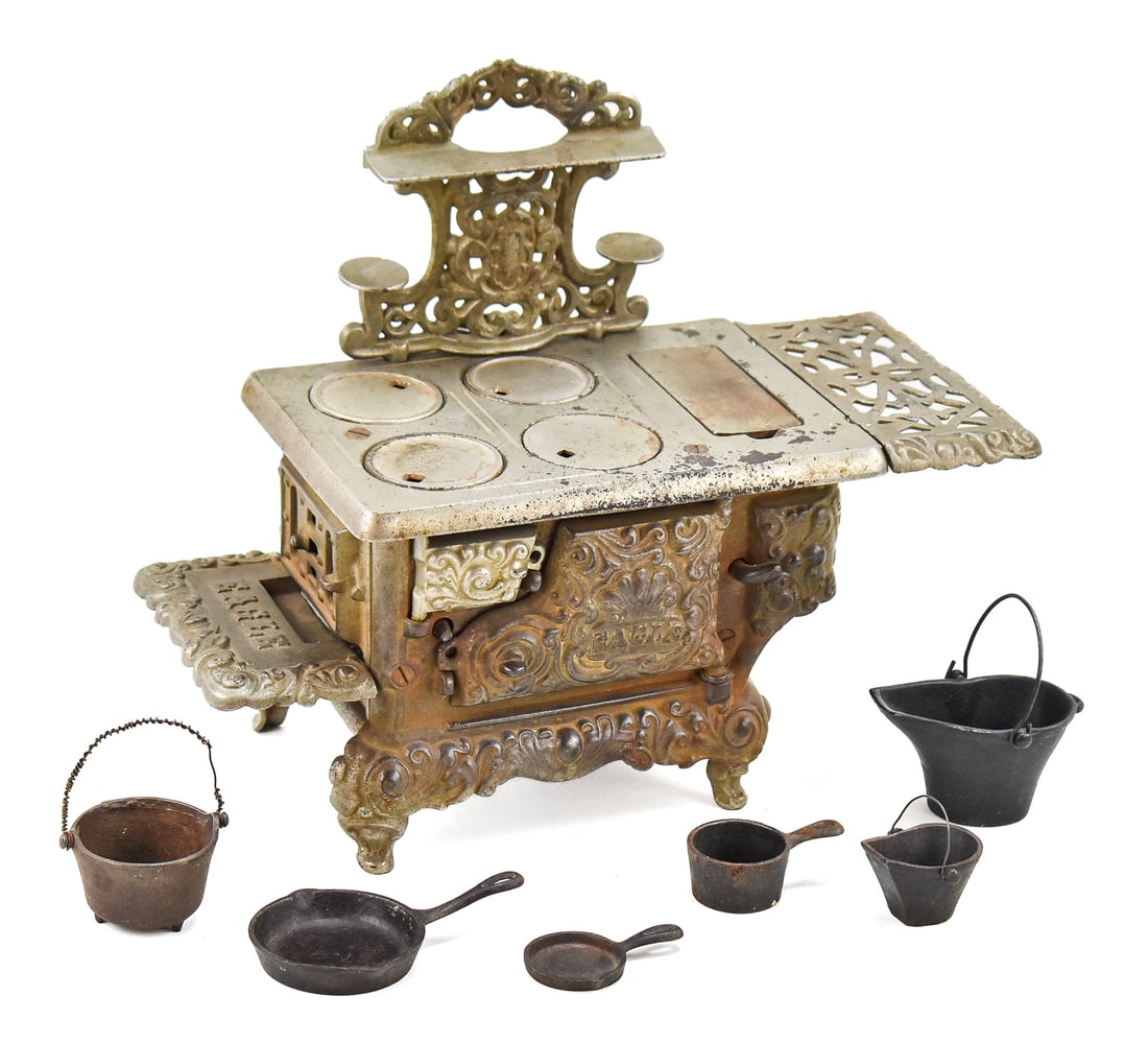 EAGLE CAST IRON MINIATURE STOVE BY HUBLEY, C. 1930s: An Eagle cast iron miniature stove manufactured by Hubley of Lancaster, Pennsylvania circa 1930s. This item comes with the two side trays, back addition, and six miniature pots and pans. It is