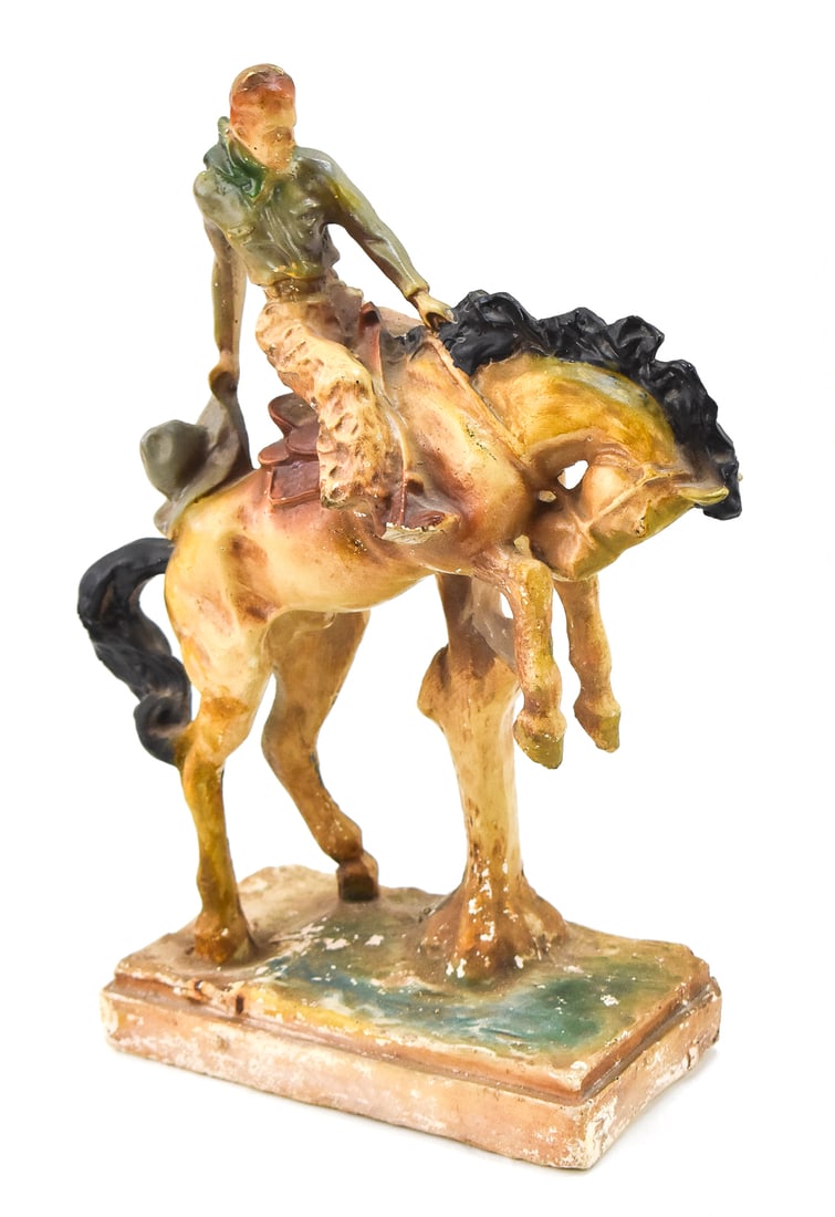 POLYCHROME CHALKWARE COWBOY ON A BUCKING BRONCO; EARLY 20TH CENTURY: A polychrome chalkware cowboy on a bucking bronco, circa early 20th century. The item measures 14" H, 10.5" W, 4.5" D.
